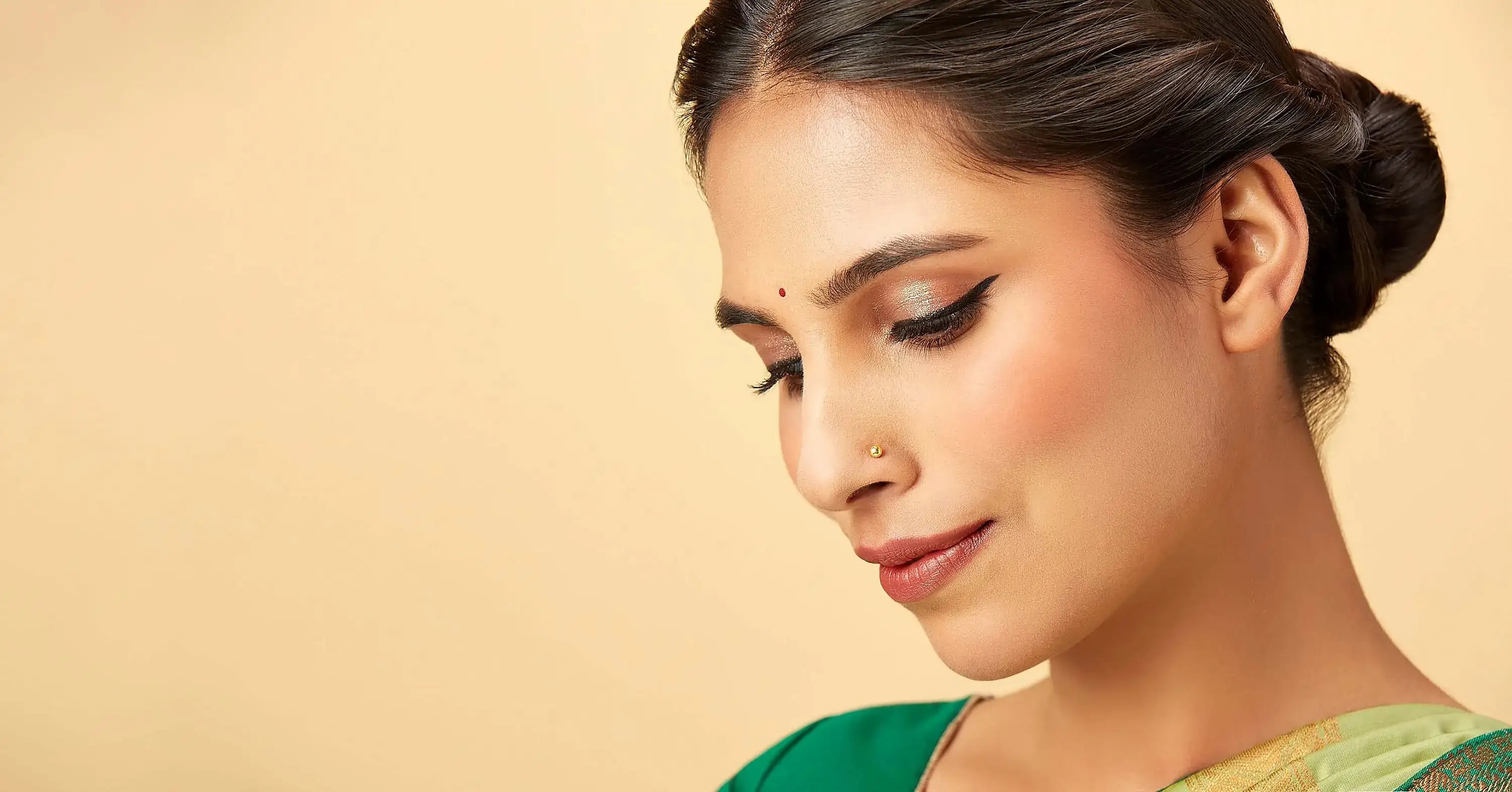 Woman wearing a minimalist 14K gold nose pin in a close-up portrait