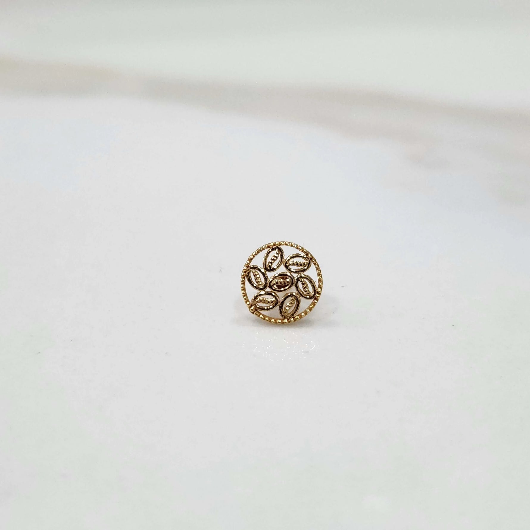 Front view of an 18K gold round nose pin on a white background displaying its floral-inspired design