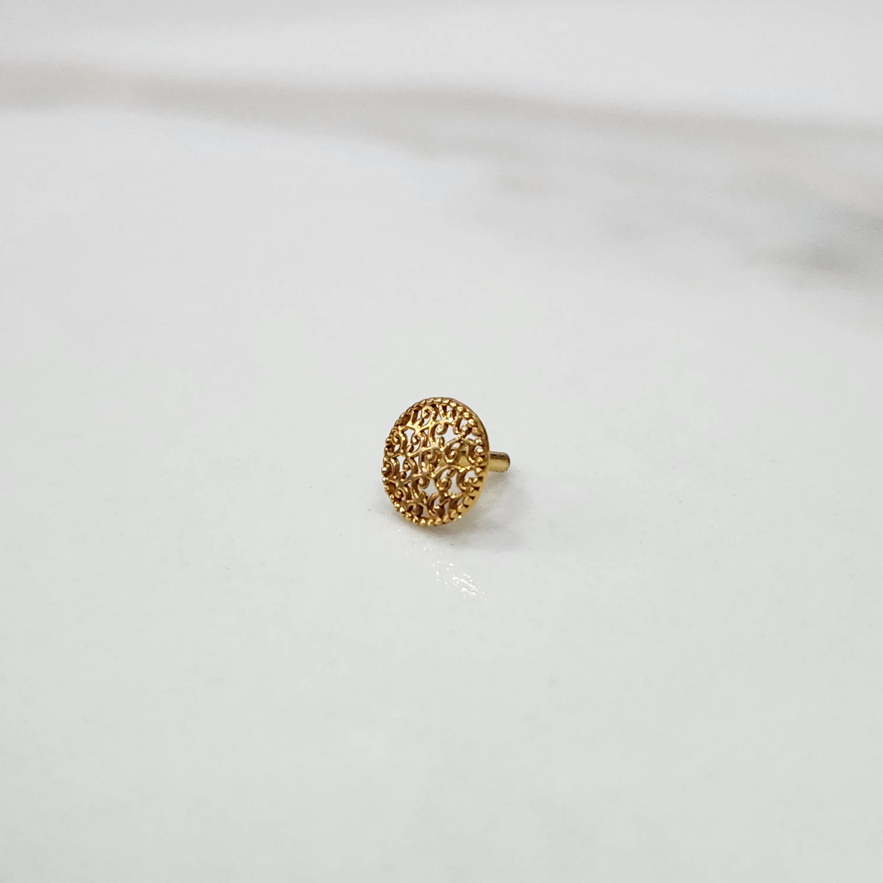 Front view of a small round gold nose pin design placed on a white background for clear design visibility