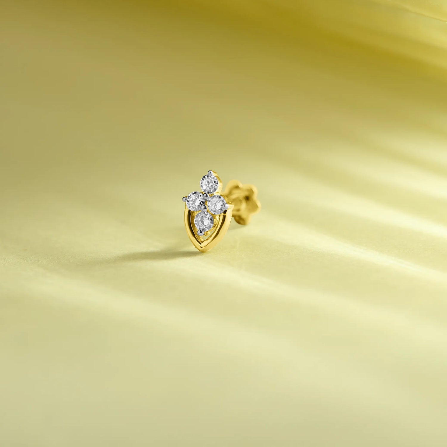 Gold leaf-shaped diamond nose pin design on soft pastel background