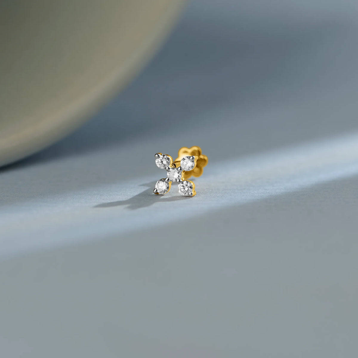 Trending gold nose pin with floral diamond design on soft blue background