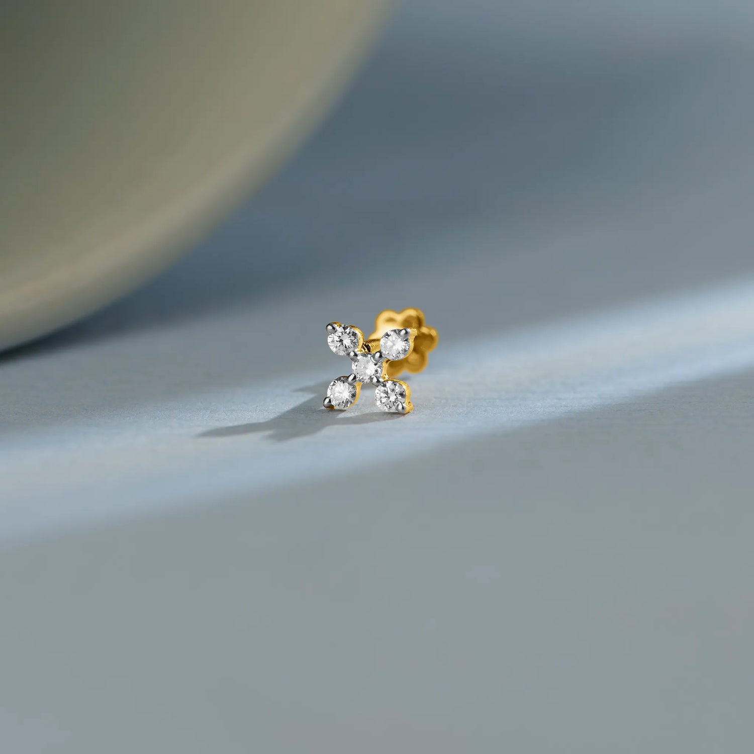 Trending gold nose pin with floral diamond design on soft blue background