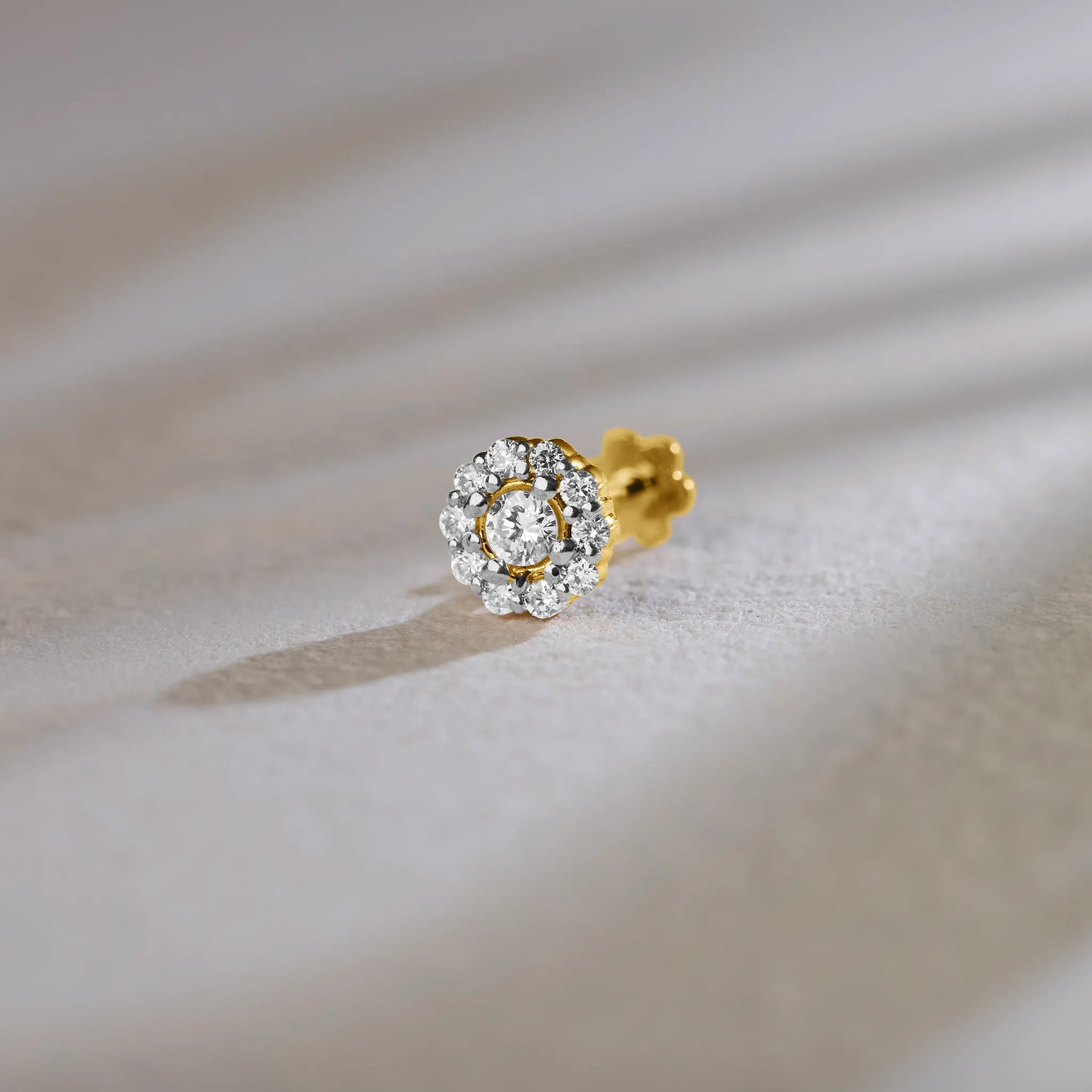 Round halo lab grown gold nose pin with center diamond on soft background
