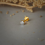 Simple gold nose pin design with a single sparkling solitaire stone set in a polished gold base on a soft neutral background