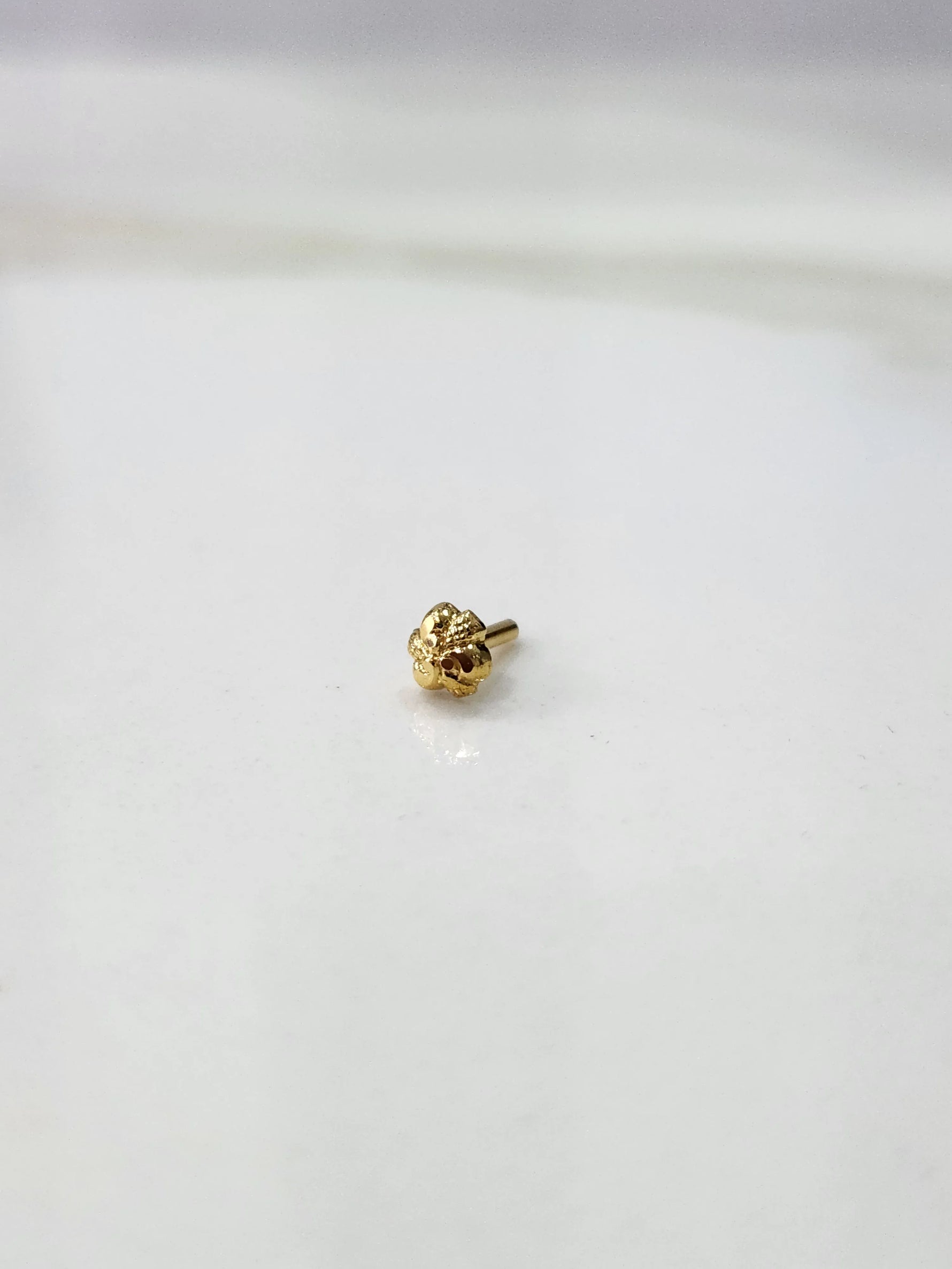 Front view of a small gold nose pin on a white background showing its compact lightweight design