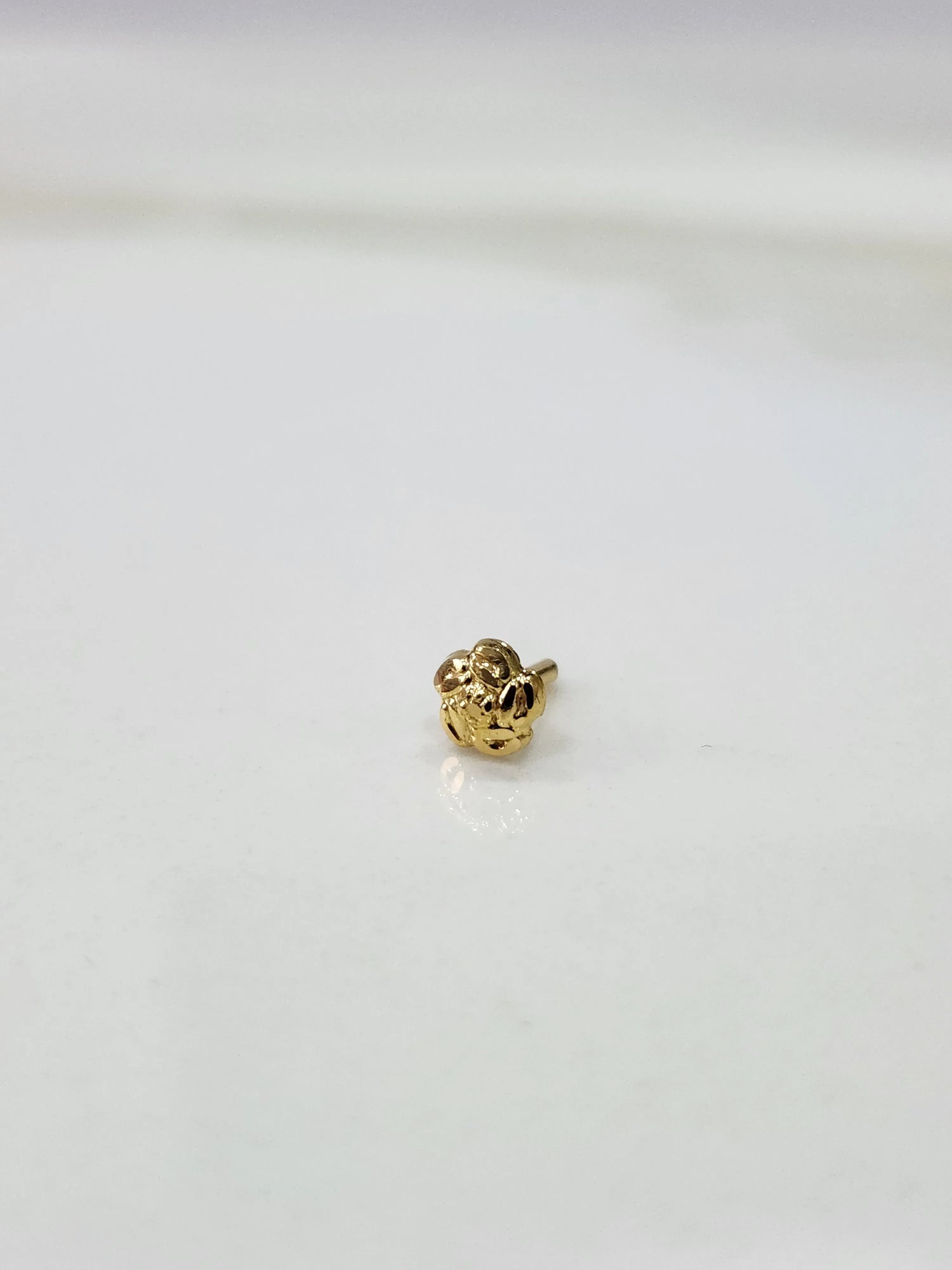 Front view of a small gold nose pin on a white background showing compact size and clean detailing