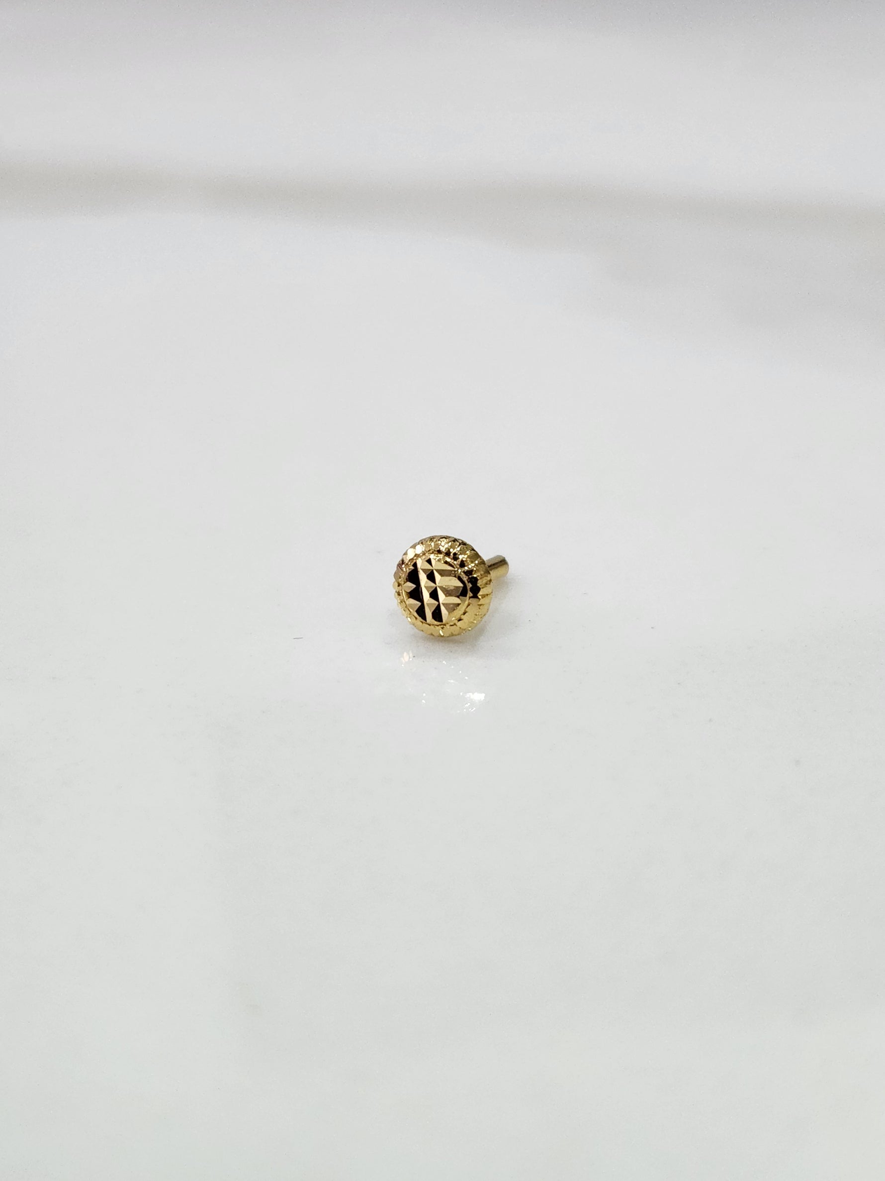 Side view of handcrafted 18k circular gold nose pin design featuring polished finish and intricate detailing