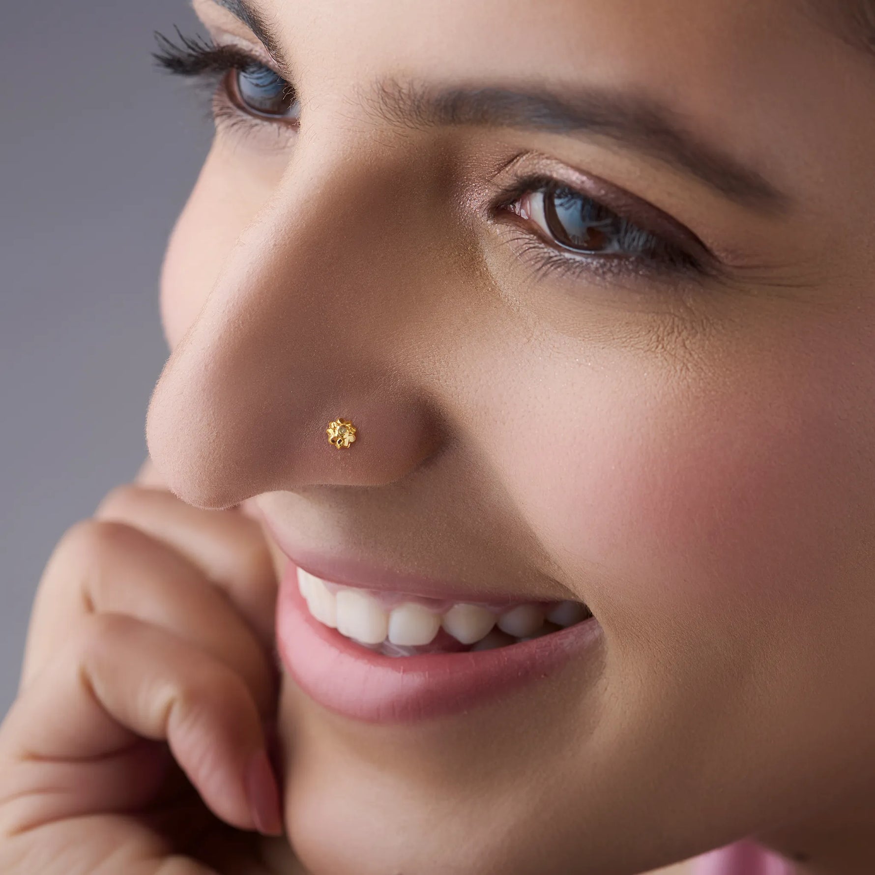 Woman wearing a minimal gold nose pin shown in a soft smiling profile for an elegant everyday look