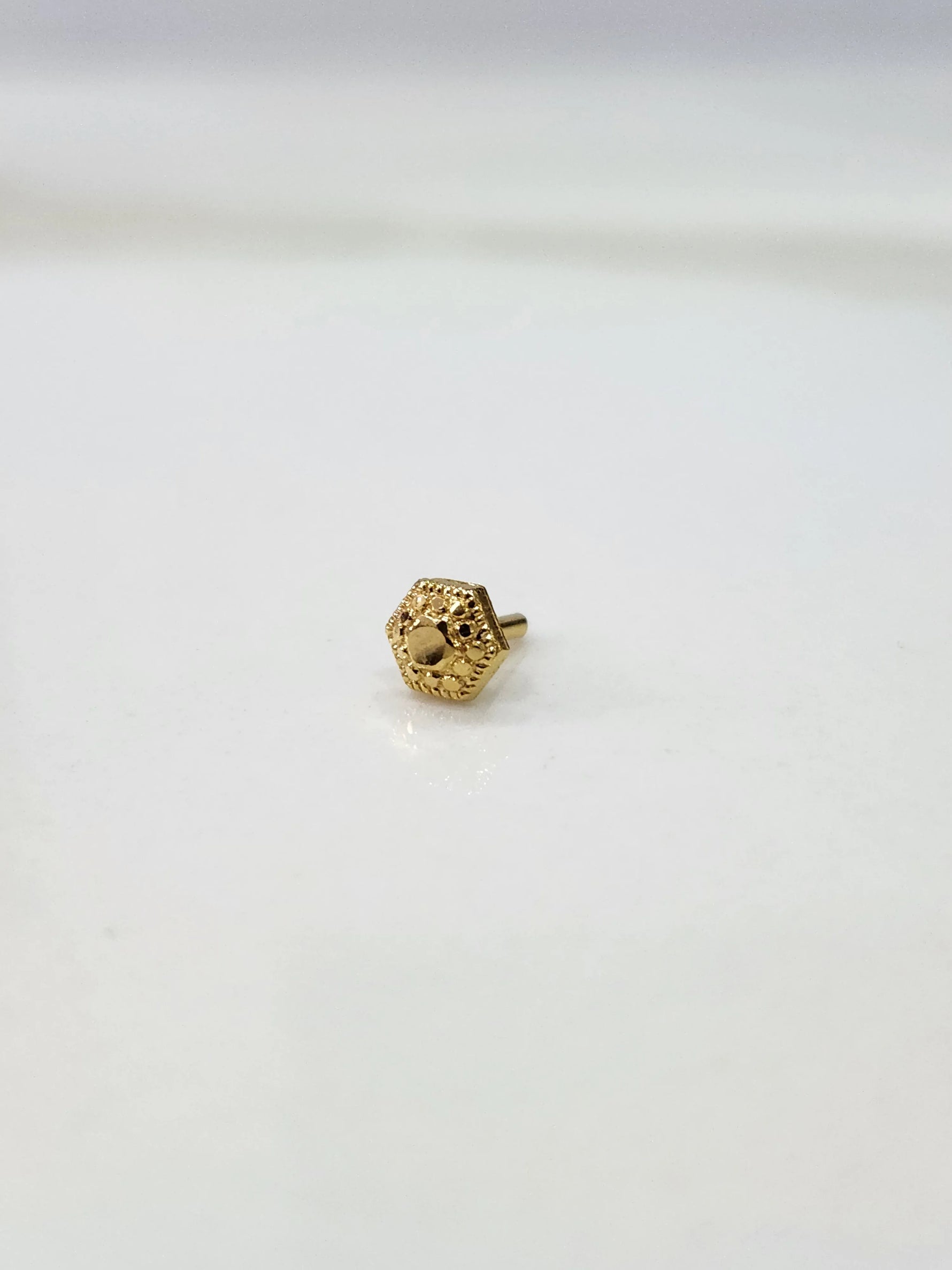 Small 18K Nose Pin Gold placed on a white surface showing fine craftsmanship