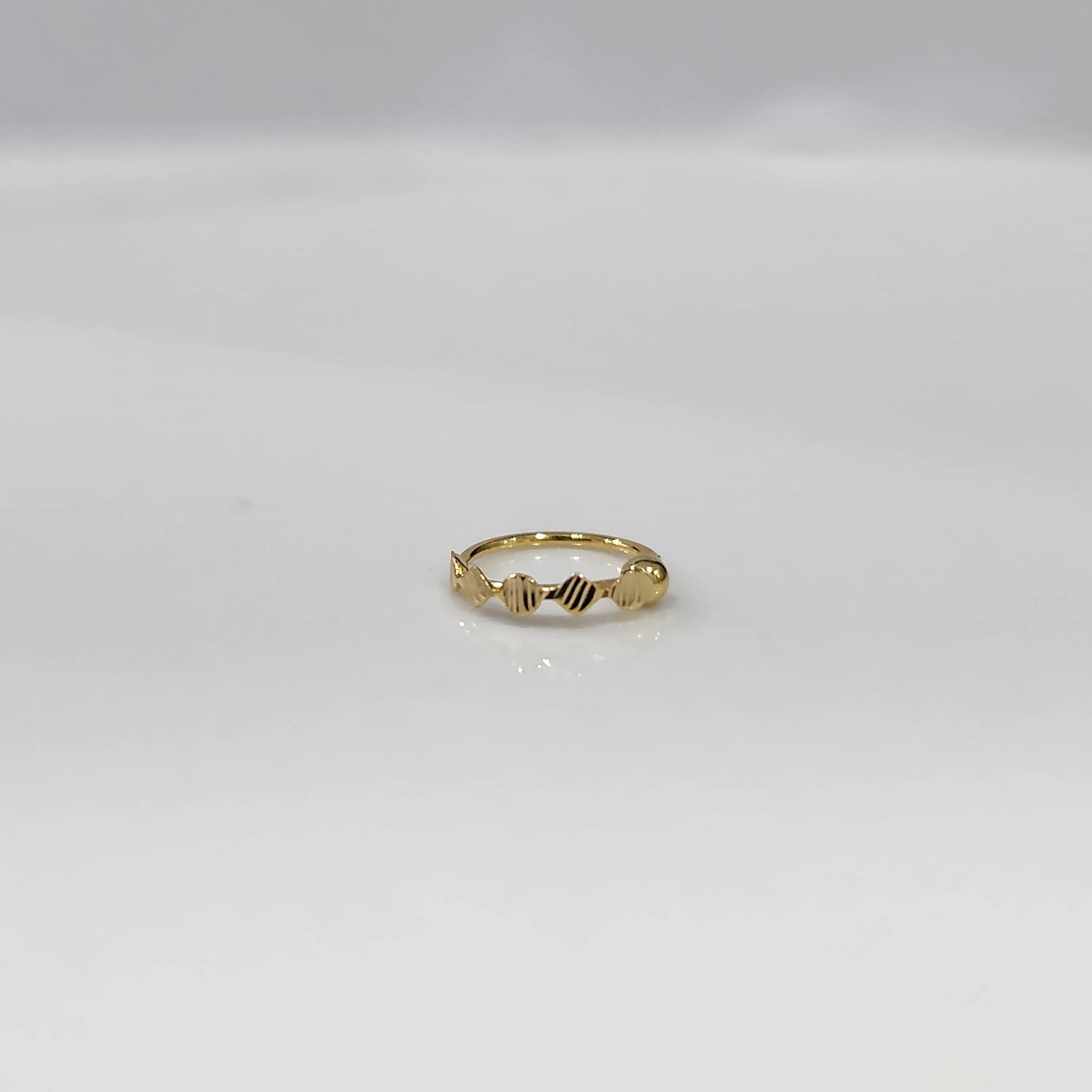 Top view of a petite 18K gold nose ring placed flat on a clean white surface