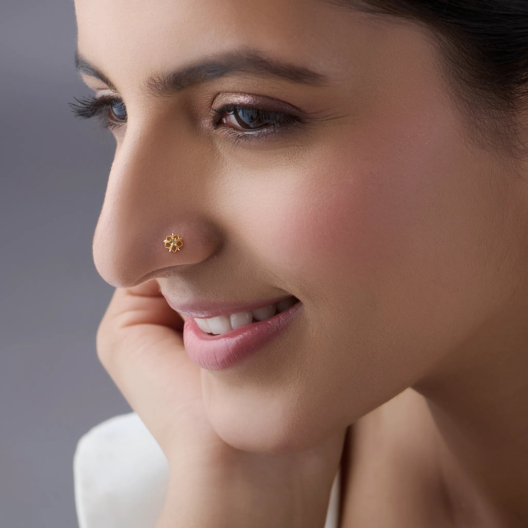 Side profile of a woman wearing a minimal 18K gold floral nose pin showing its subtle and refined appearance