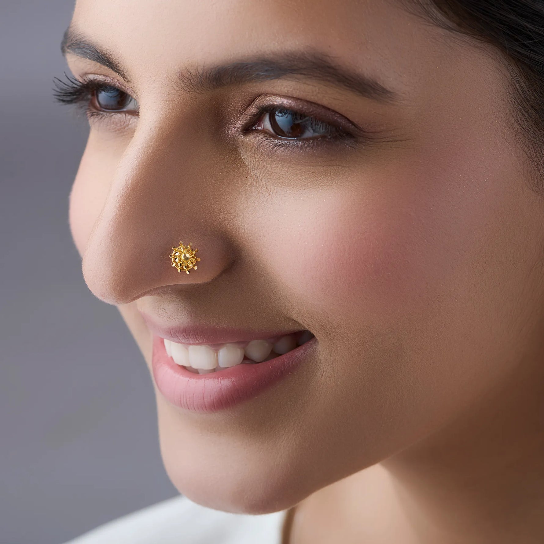 Woman wearing elegant gold nose pin design highlighting delicate floral motif for everyday elegance