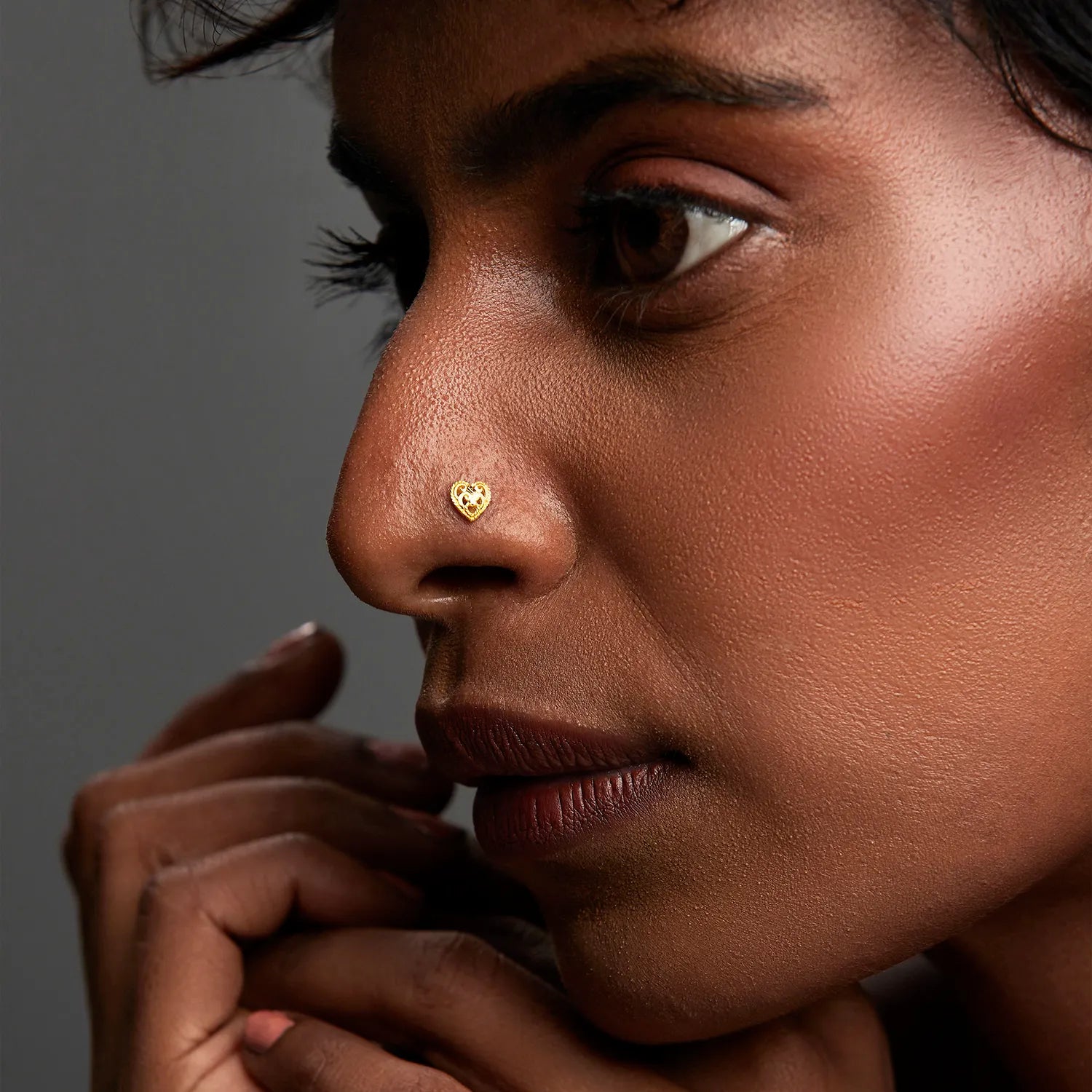 Woman wearing an elegant 18K heart gold nose pin highlighting a minimal and sophisticated look