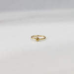 Flat lay view of small open hoop gold nose ring on a white surface showing its petite size