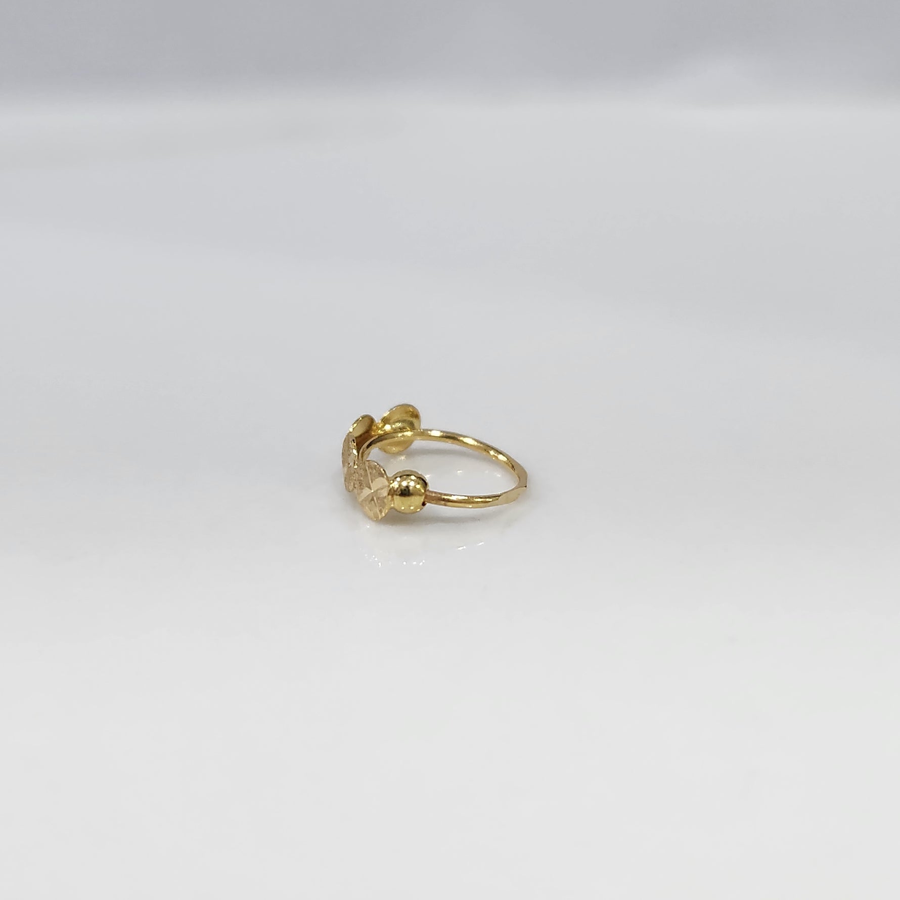 Crossbeam Circles gold nose ring in 18K gold displayed on a flat surface, featuring circular cross patterns with an elegant design