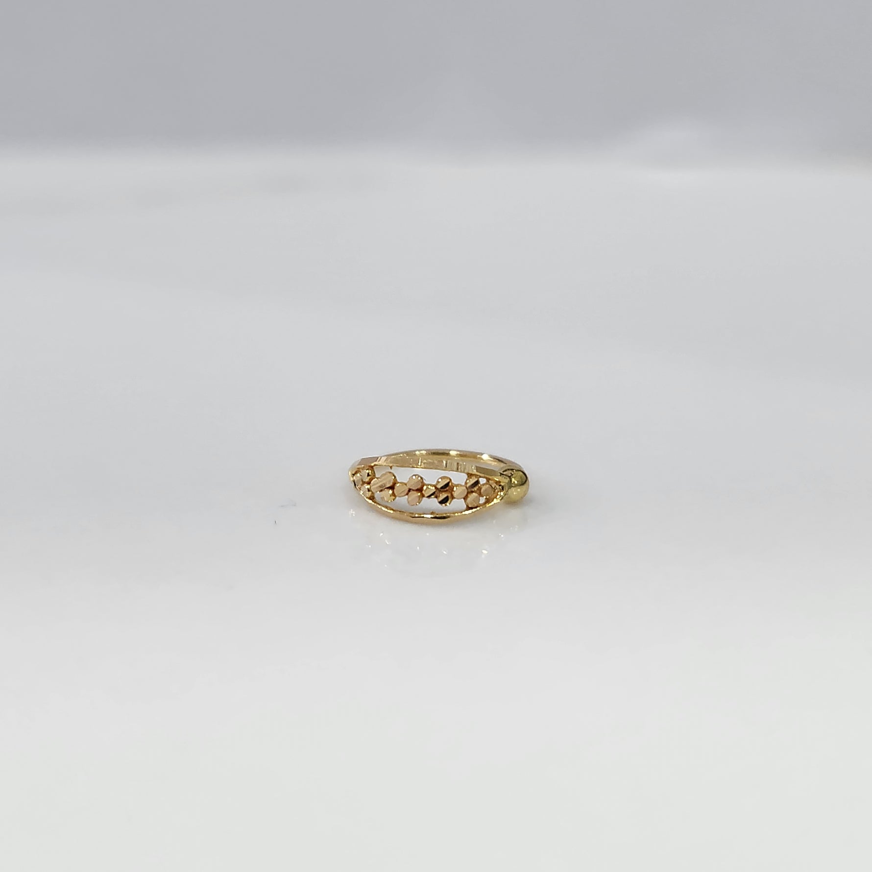 Petite Garland Gold Nose Ring crafted in 18K gold with delicate floral garland design displayed on a flat lay surface by Yuvora