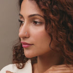 J type nose pin gold worn on the nose in a close-up portrait, showcasing a modern and elegant everyday jewelry look