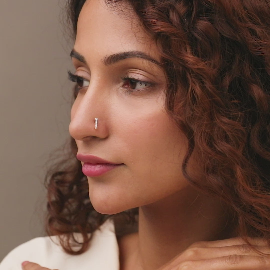 J type nose pin gold worn on the nose in a close-up portrait, showcasing a modern and elegant everyday jewelry look